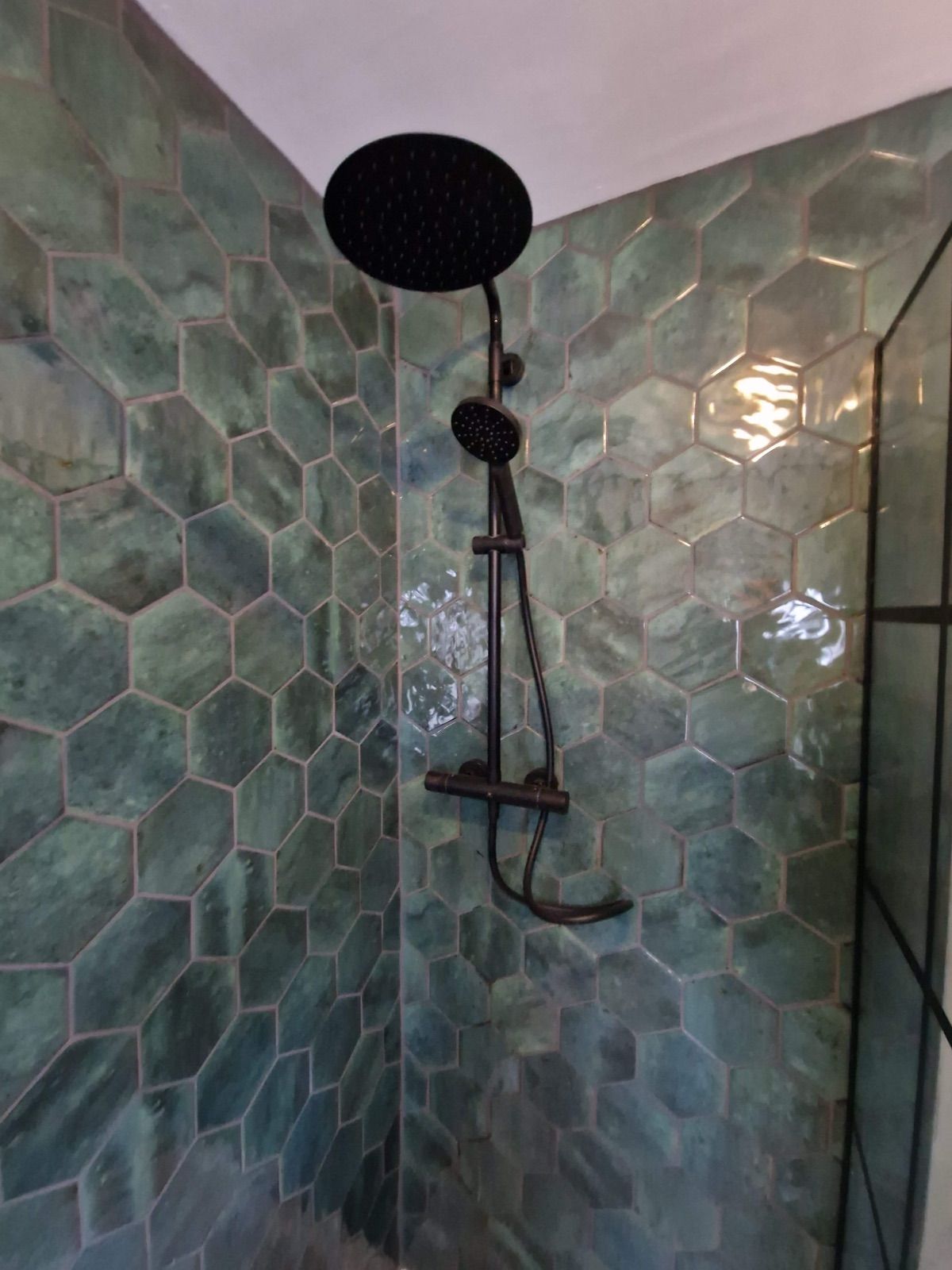 Walk-in shower with green hexagon tiles and matt black rainfall shower