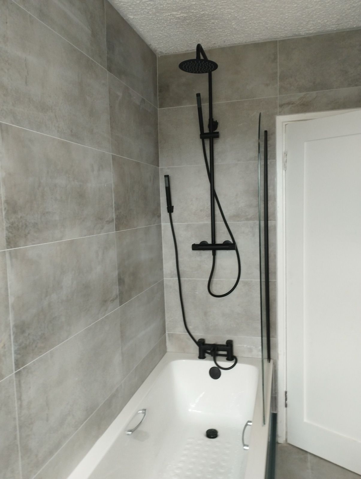 Grey-tiled bathroom with matt black shower over bath