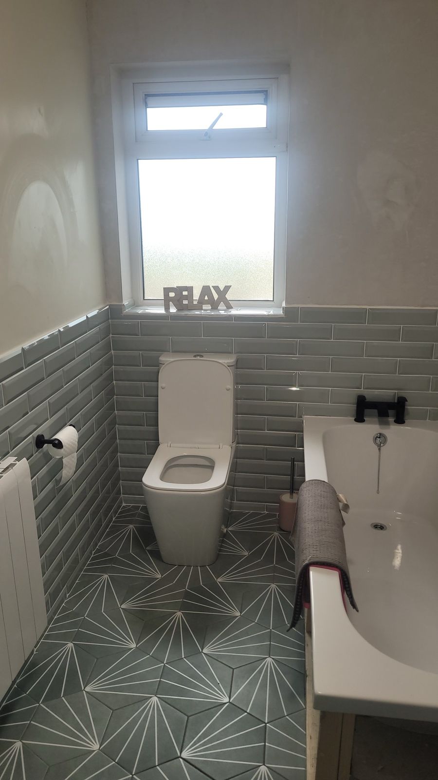 Renovated family bathroom with sage tiles and star-pattern floor